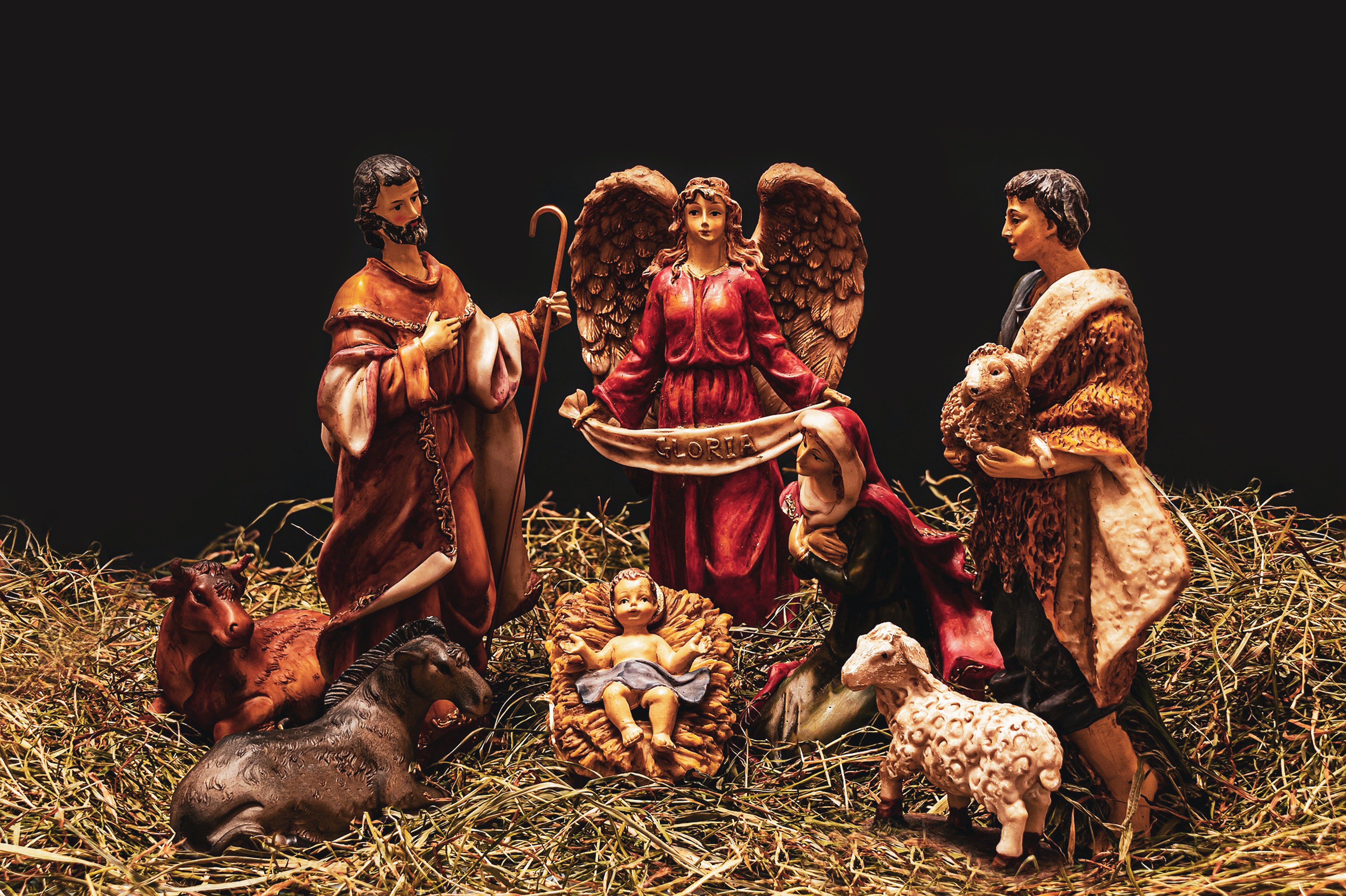 Darstellung einer Krippe mit dem neugeborenen Jesus, seinen Eltern Maria und Josef, umgeben von Tieren und einem Engel.