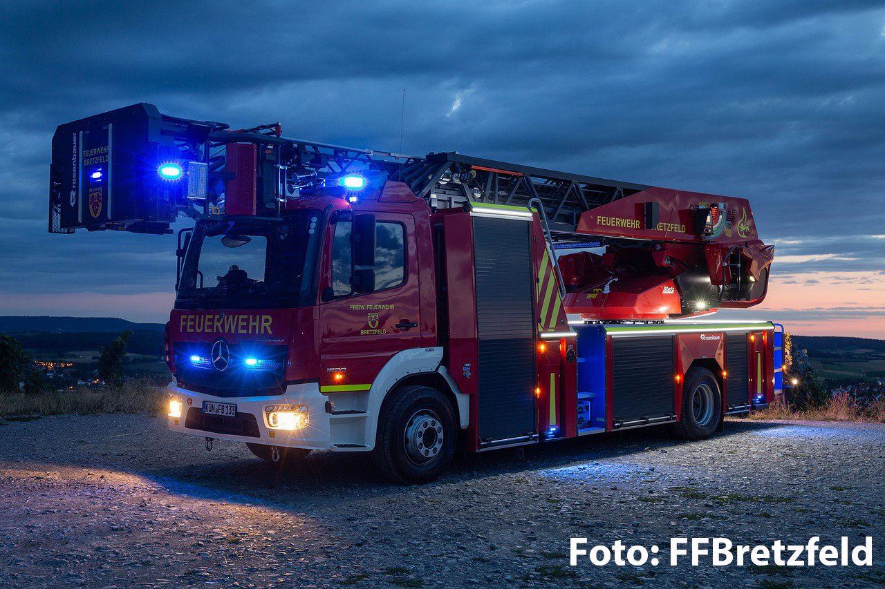 Drehleiter-Fahrzeug der Feuerwehr in der Dämmerung mit Blaulicht. 