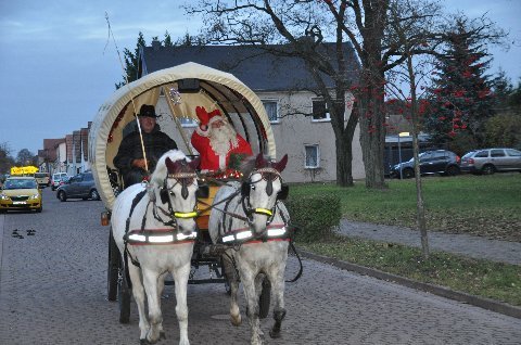 Eine Kutsche mit weißen Pferden und dem Weihnachtsmann als Kutscher.